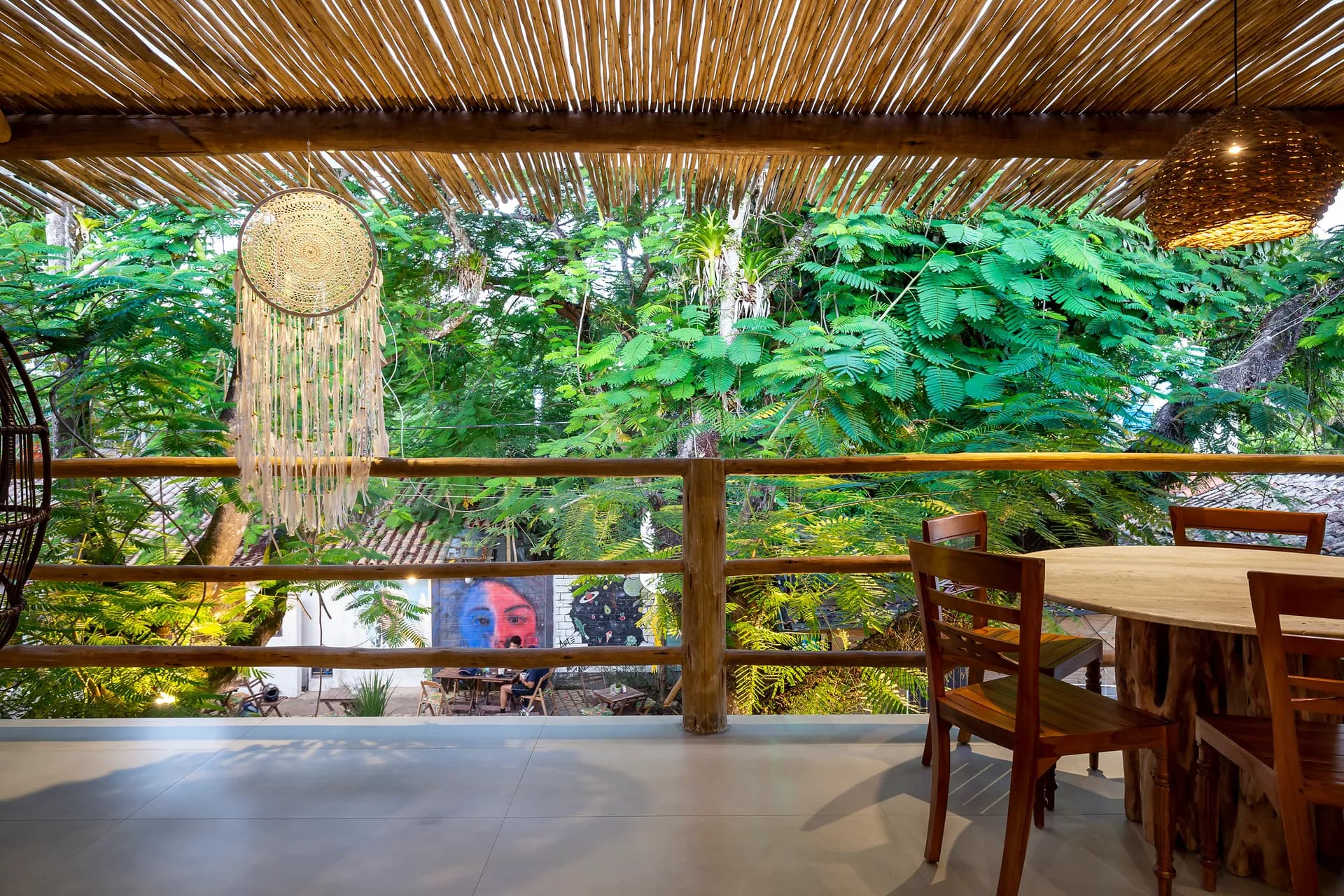 Varanda com mesa entre o verde — Casa com 3 Suítes